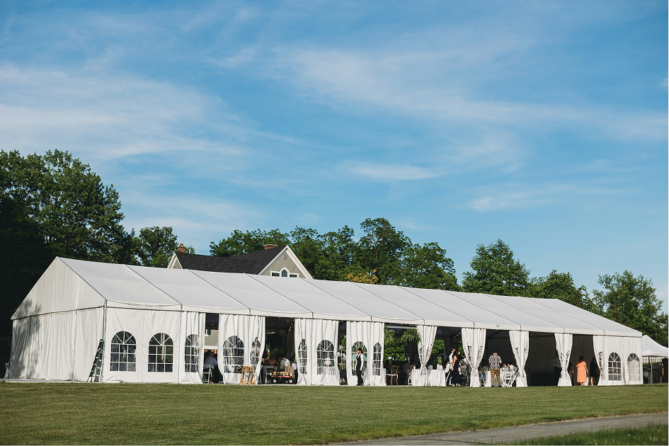 Large white event tent with windowed sidewalls on a lawn